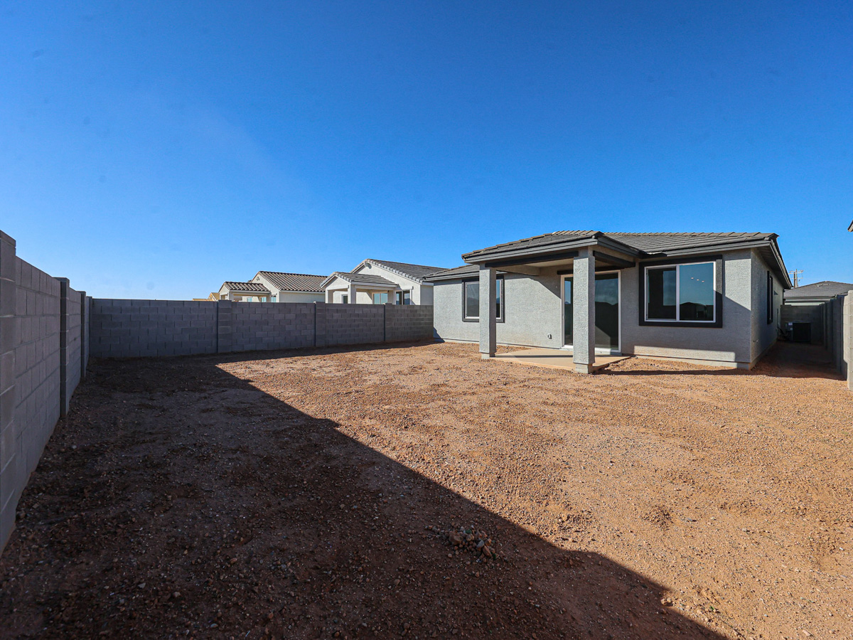 A dirt yard with a house in the background.