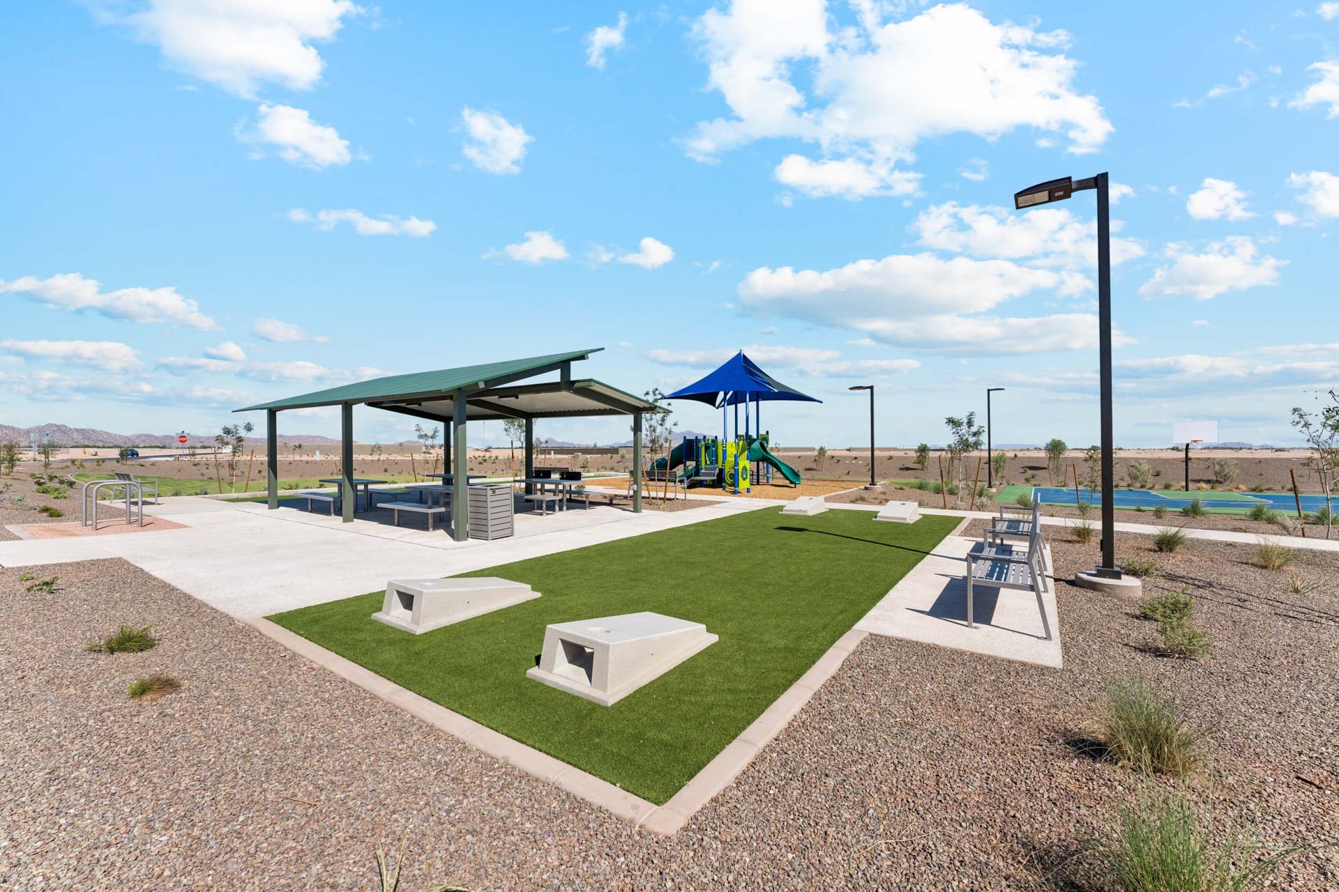 Palomino Ranch Community Amenities cornhole lawn and play structure with vibrant green turf and grass-new construction homes near amarillo ranch palomino ranch in maricopa AZ with USDA new construction