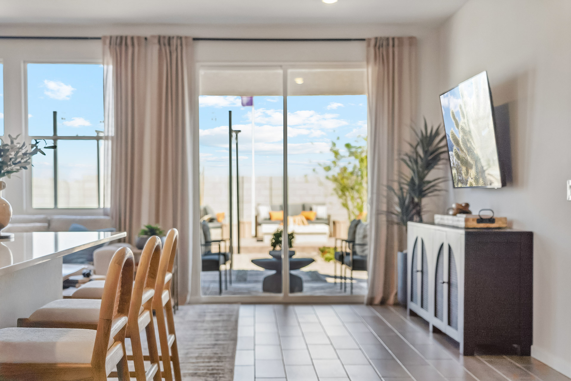 A room with a table chairs and a window with a view of the ocean.