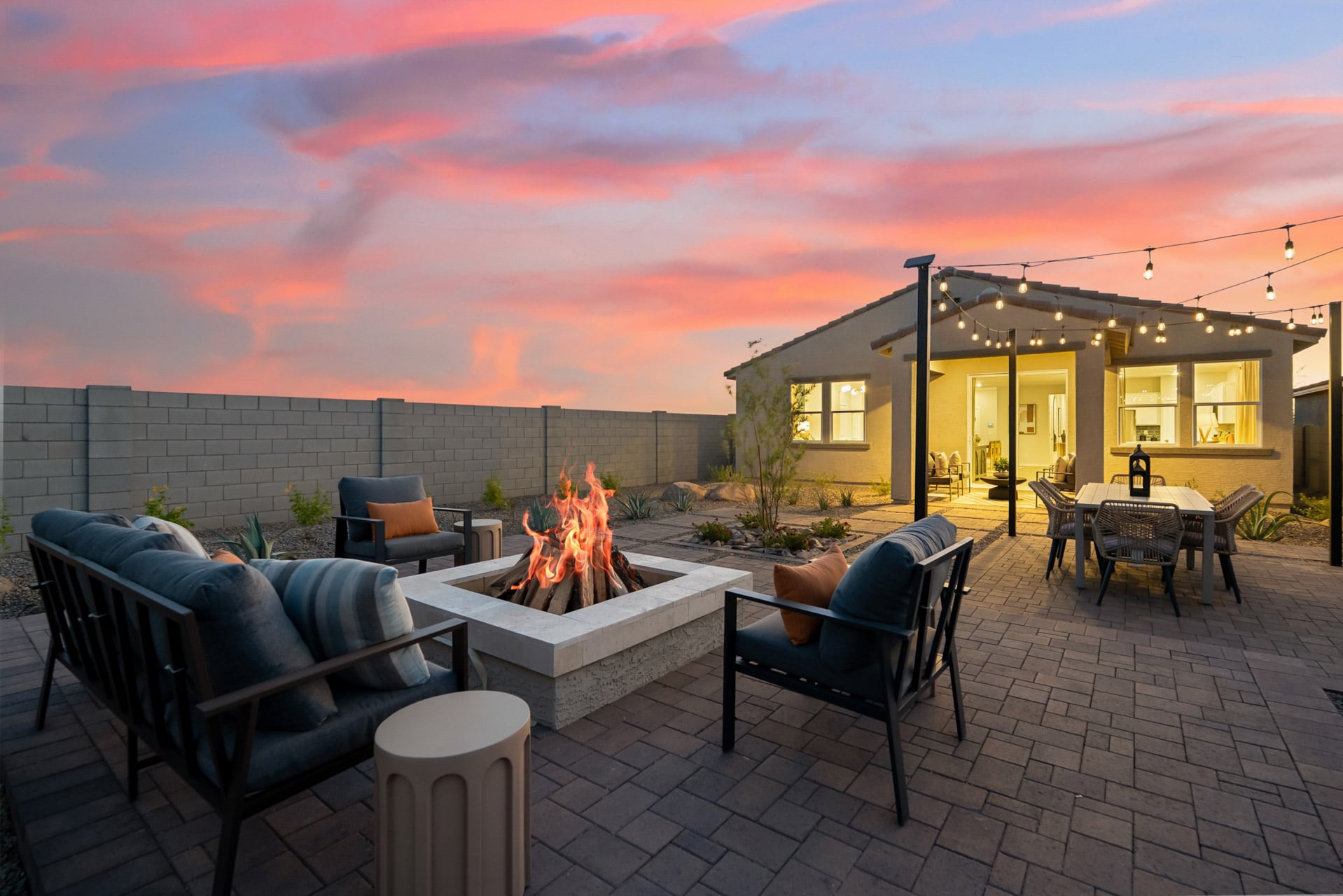 A patio with a fire pit and chairs and a fire pit.