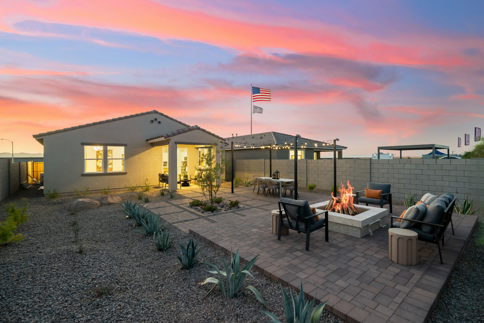 A patio with chairs and tables and a building with a sunset.