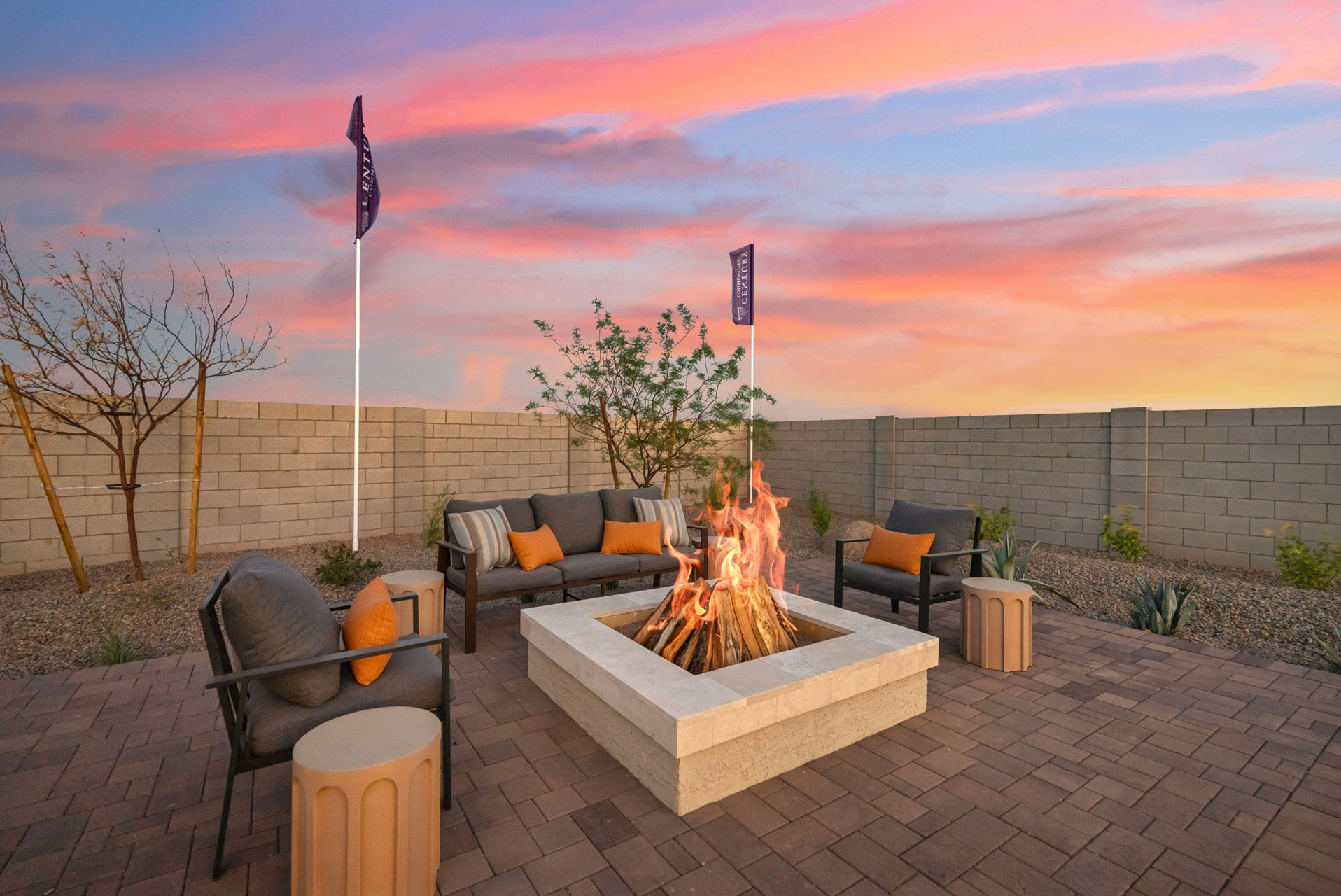 A patio with a fire pit and chairs and a flag on a sunny day.