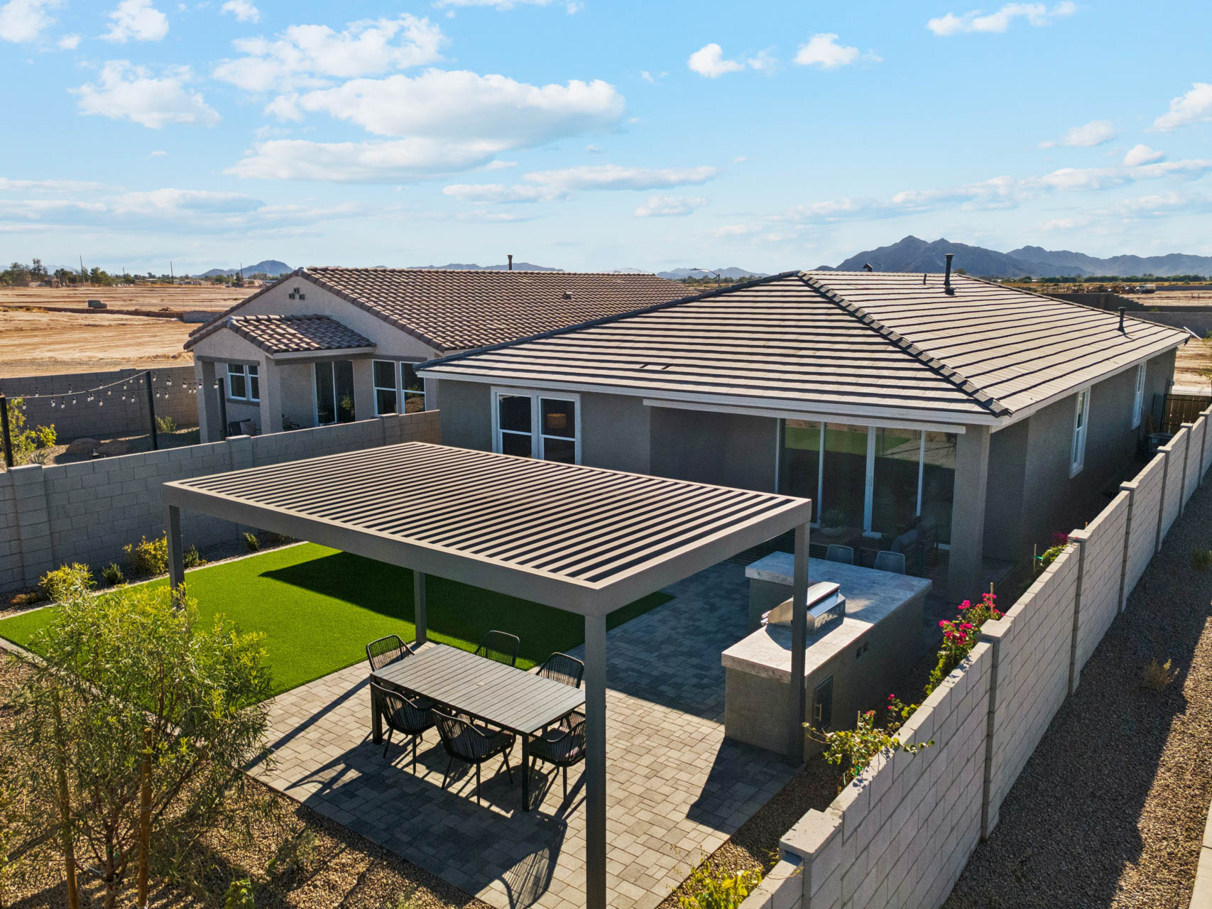 A house with a pool and a patio with a table and chairs.