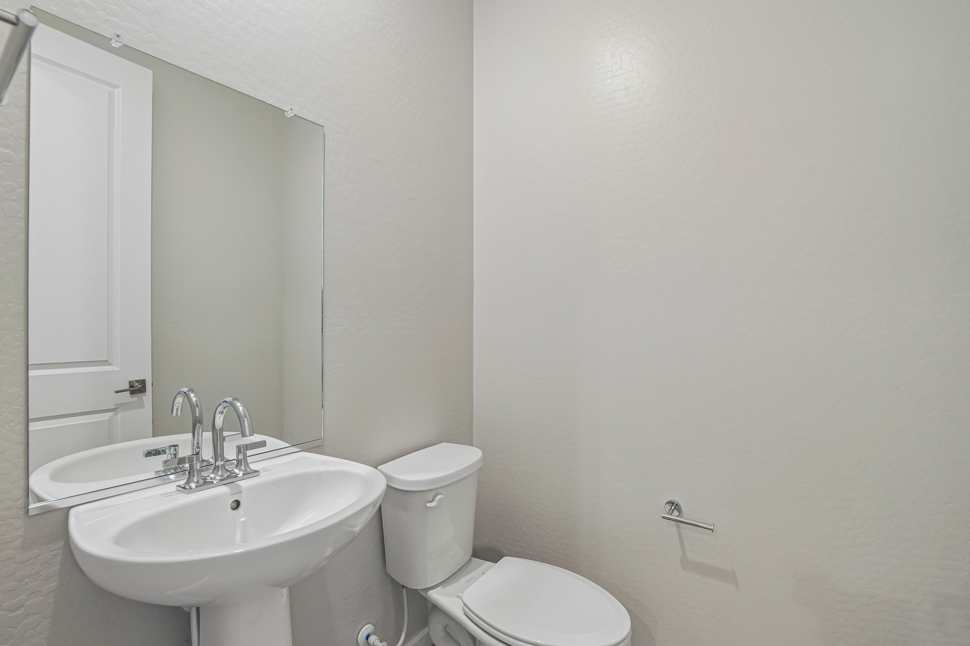 A bathroom with a toilet sink and a mirror.