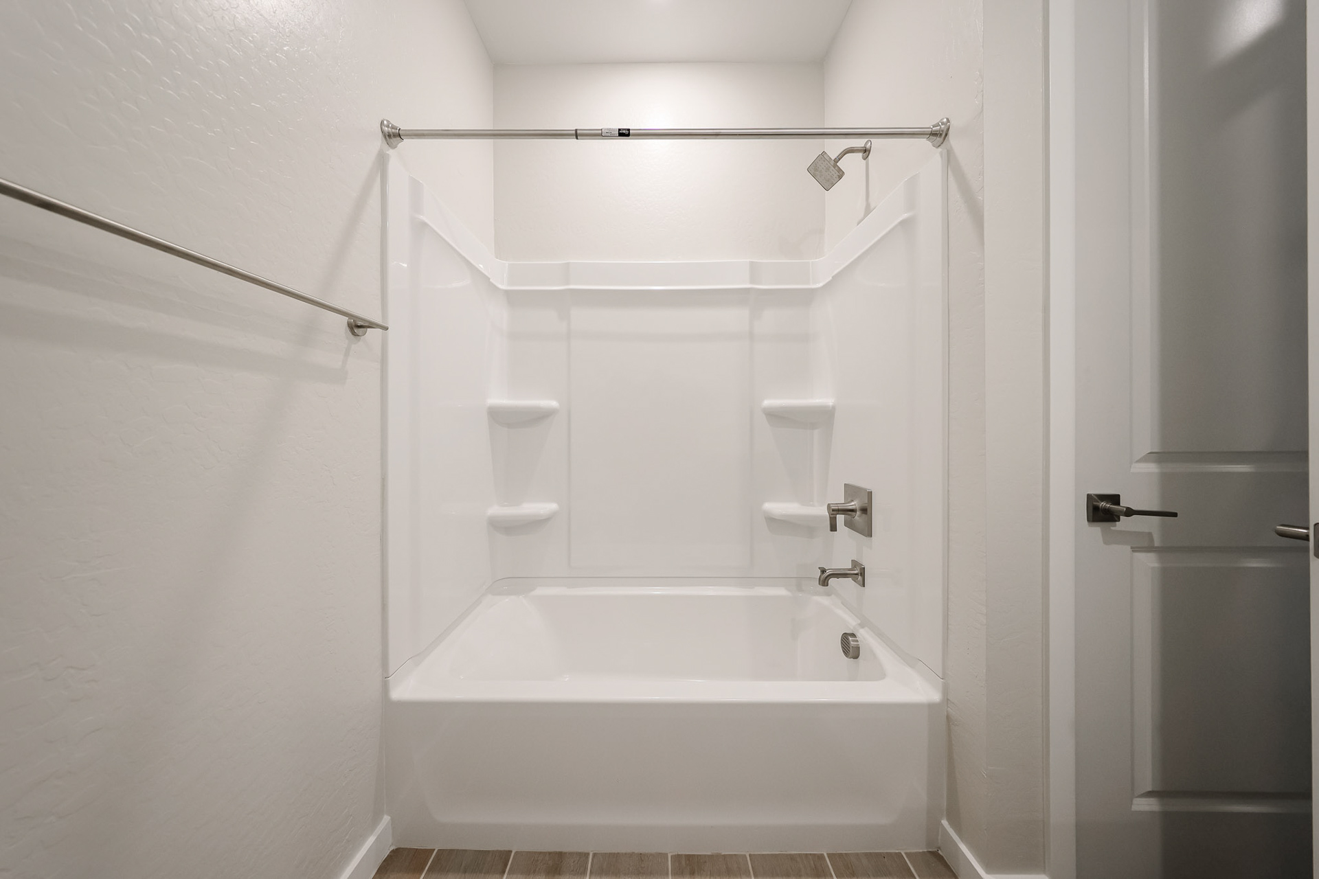 A bathroom with a bathtub and shower unit.
