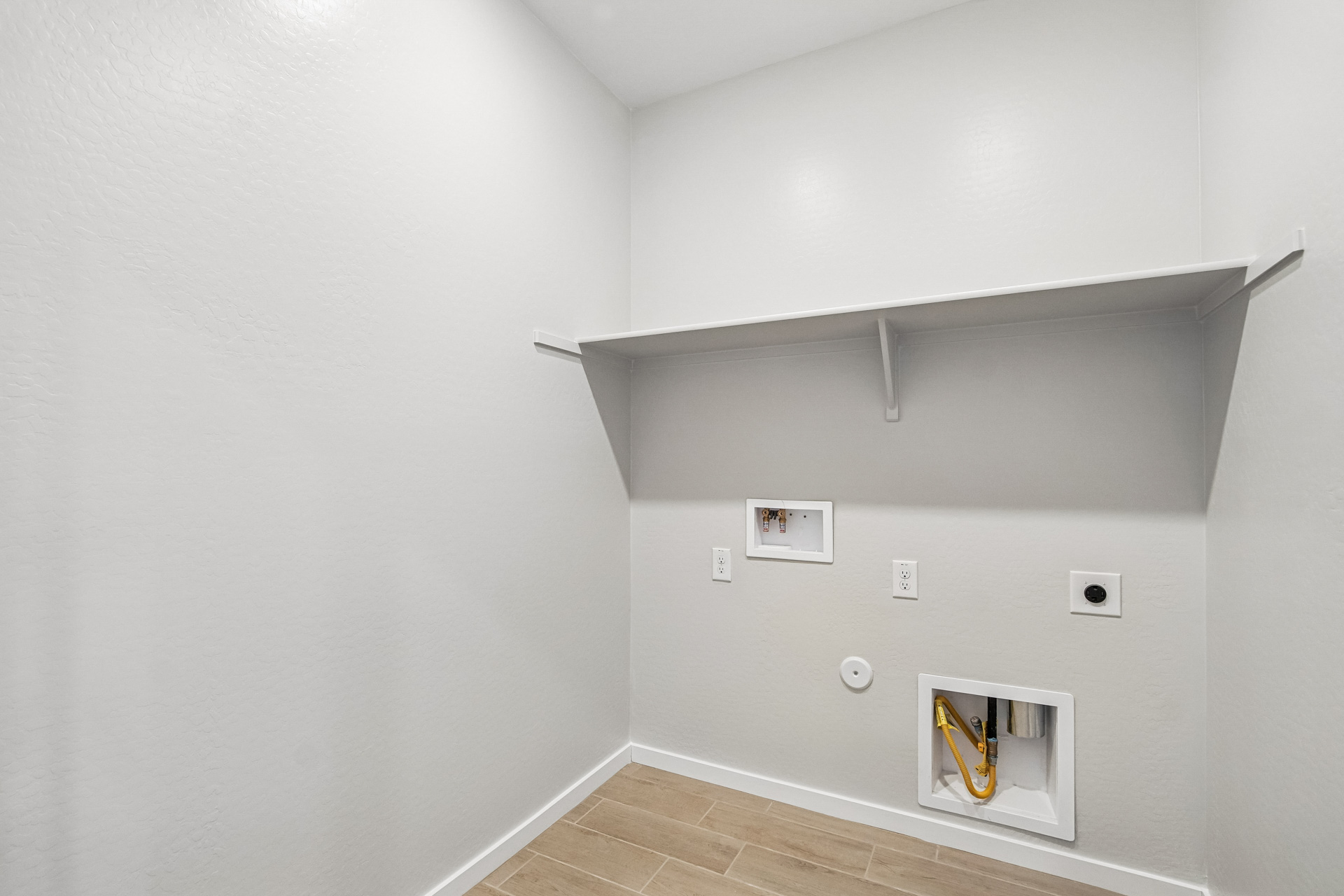 A white room with a shelf and a white wall.