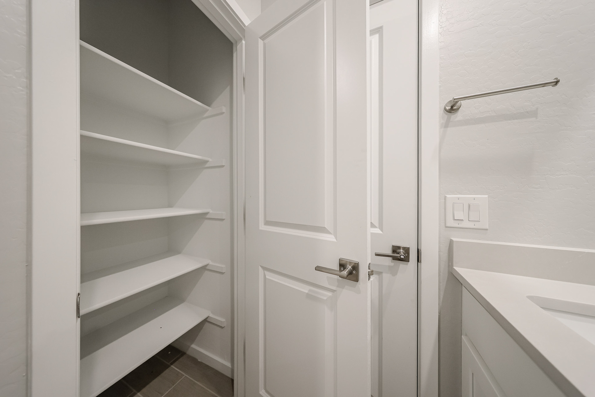 A white door next to a white shelf.