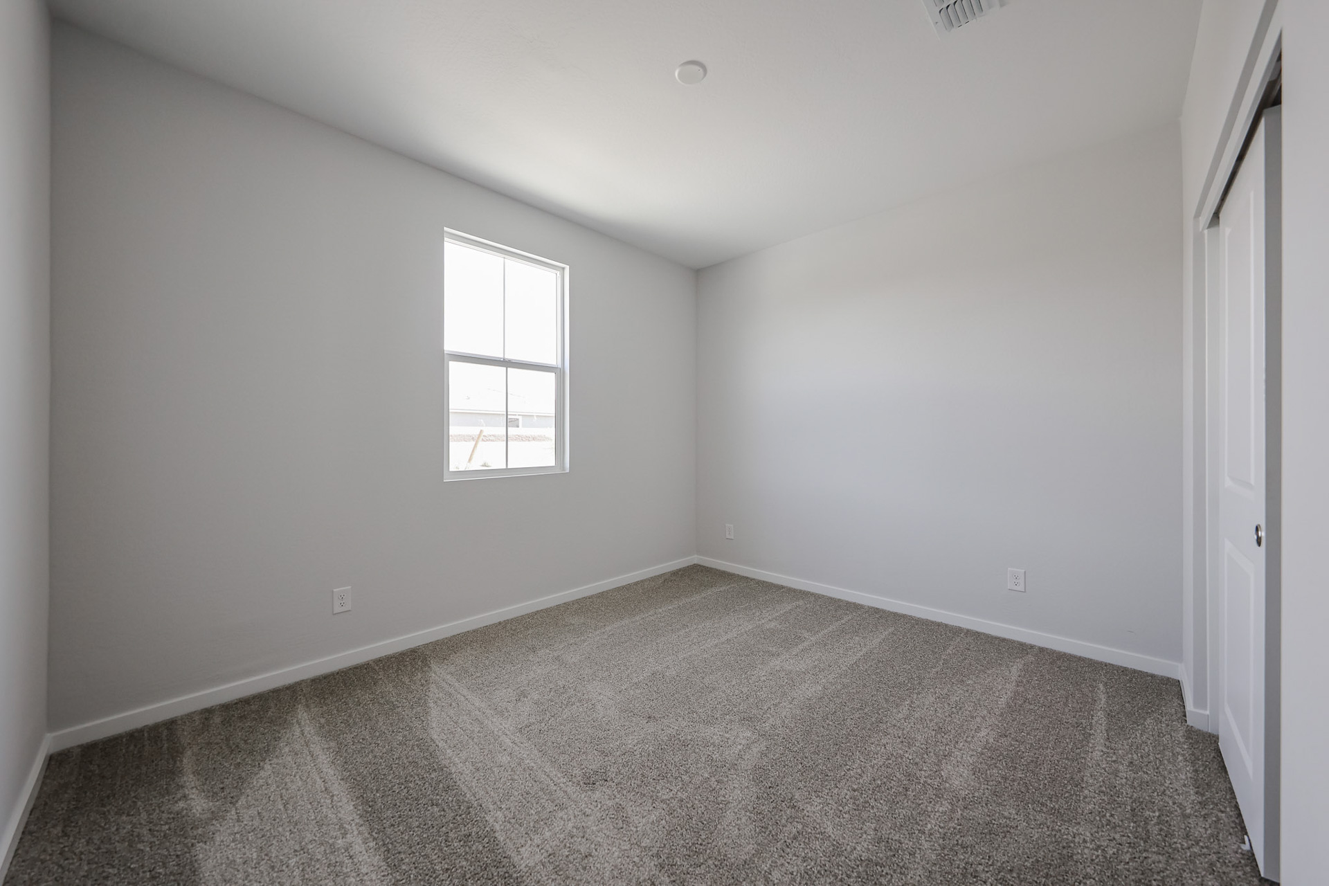 A room with a carpet and a window.