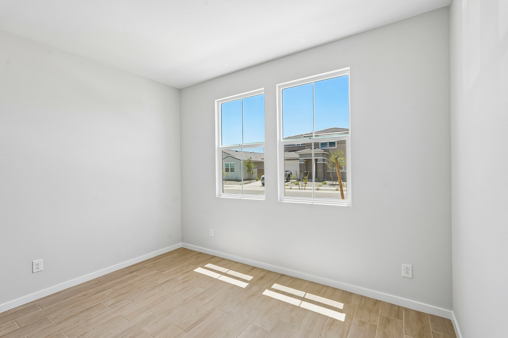 A room with a wood floor and a window with a view of the water.