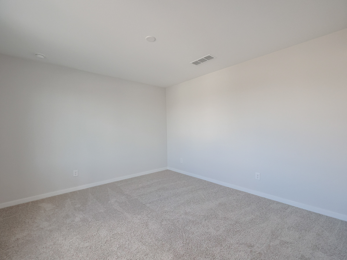 A room with a carpet and a white wall.