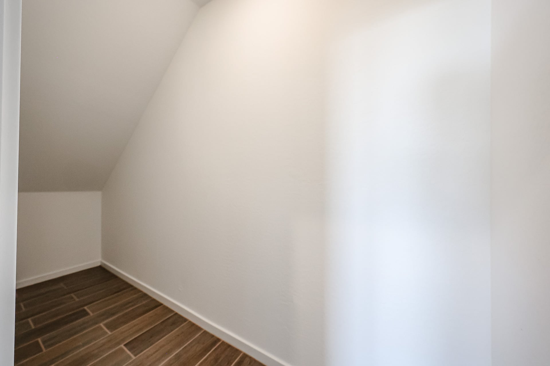 A white wall with a wood floor.