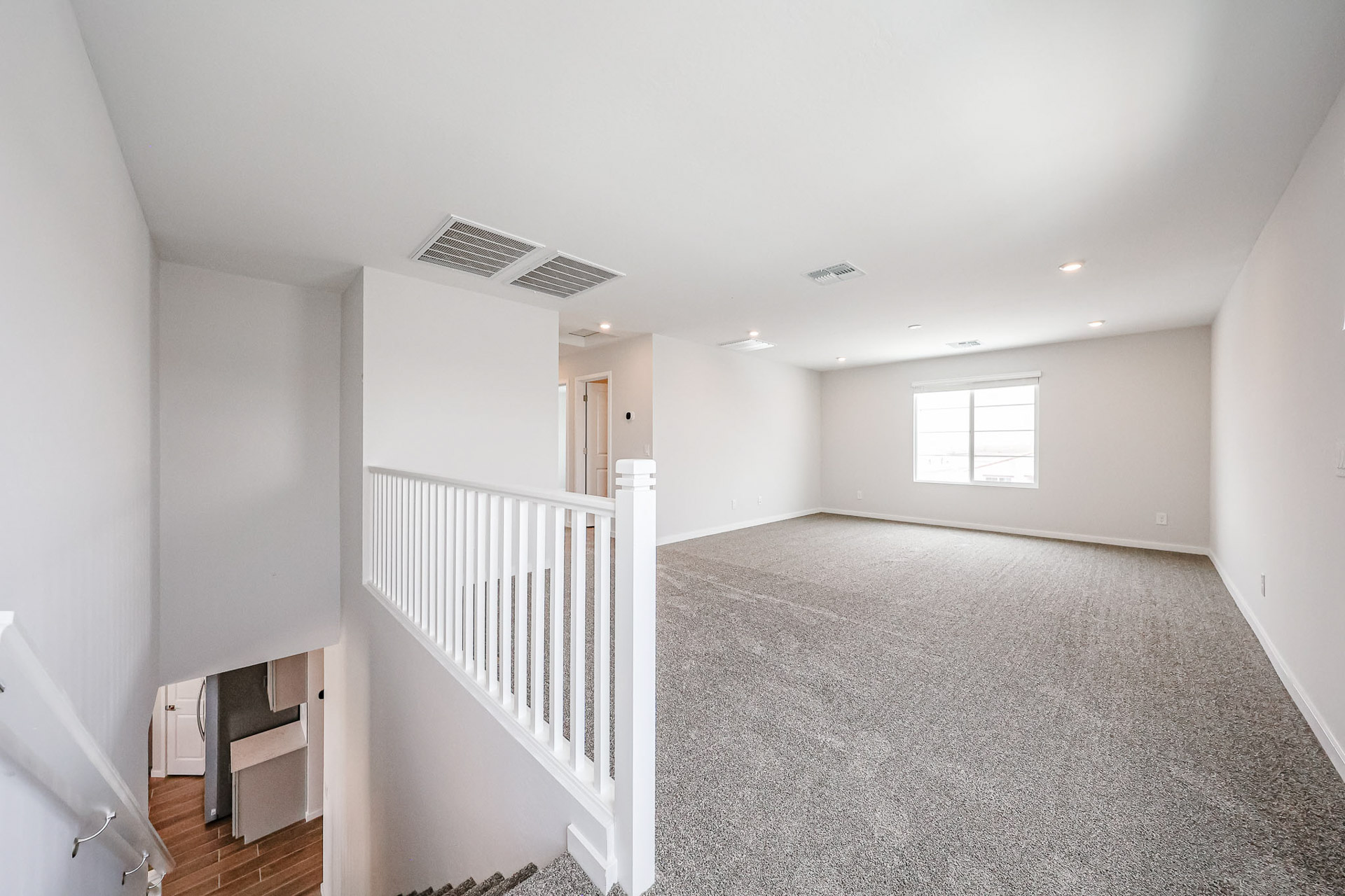 A room with a white railing and a white staircase.
