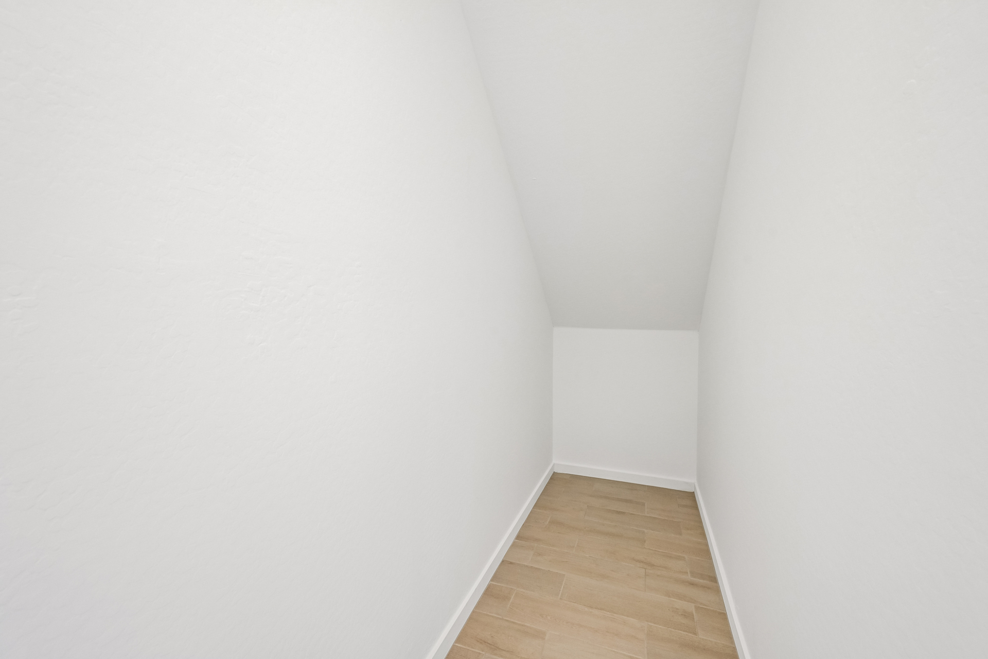 A white hallway with a wood floor.