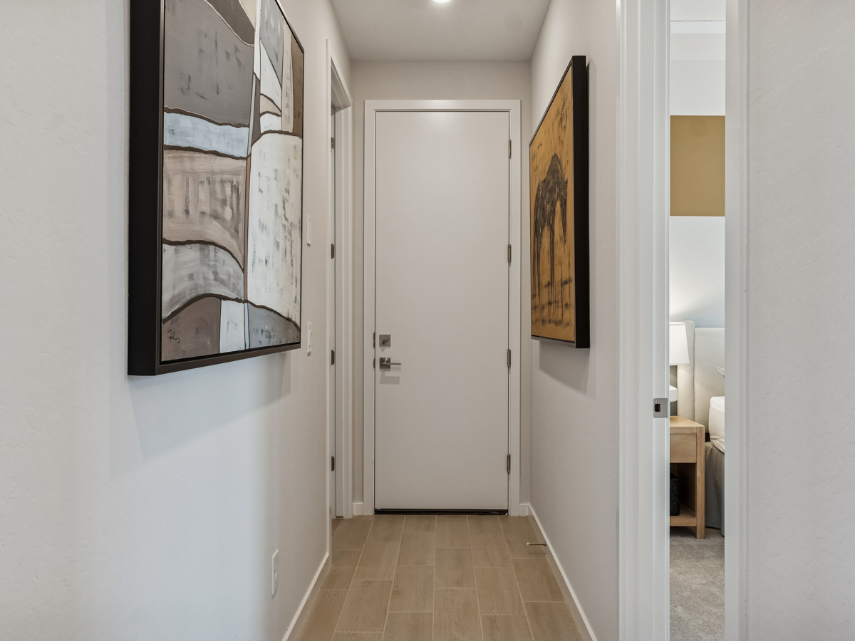 A hallway with a door and a painting on the wall.