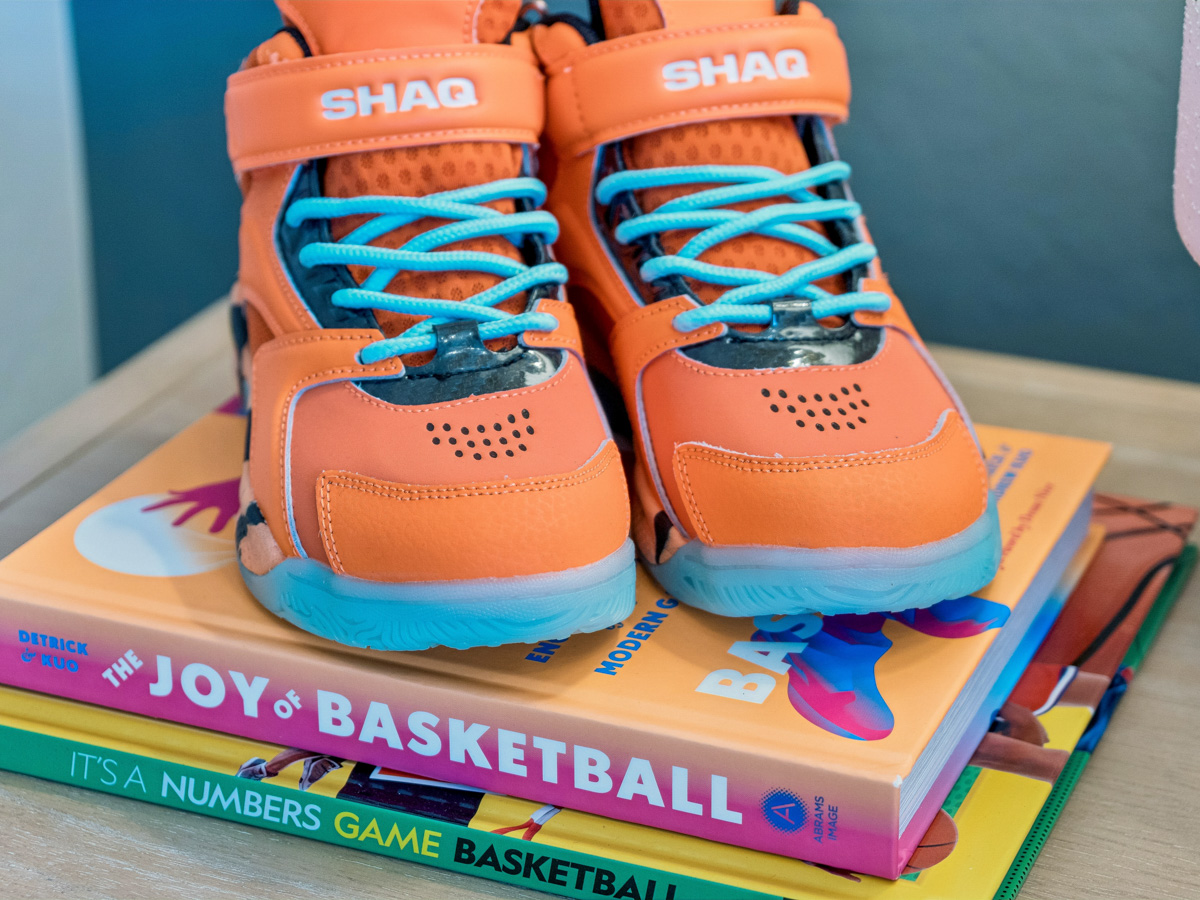 A pair of orange and blue shoes on a stack of books.