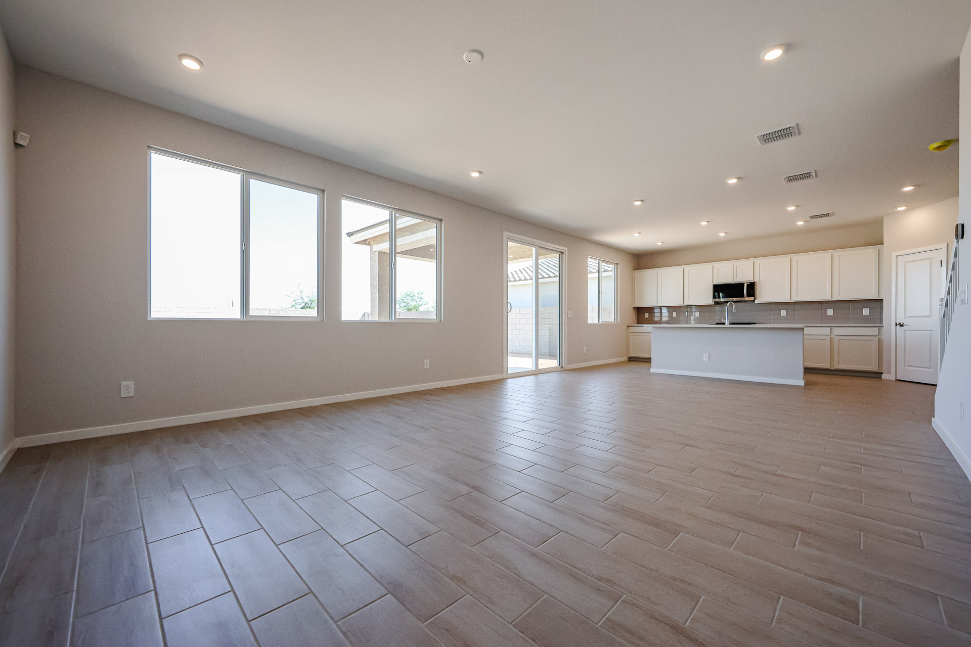 A large empty room with a wood floor and white cabinets.