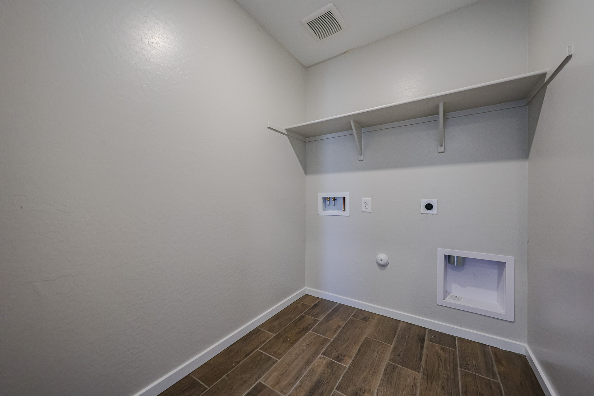 A room with a tile floor and a white wall with a vent.