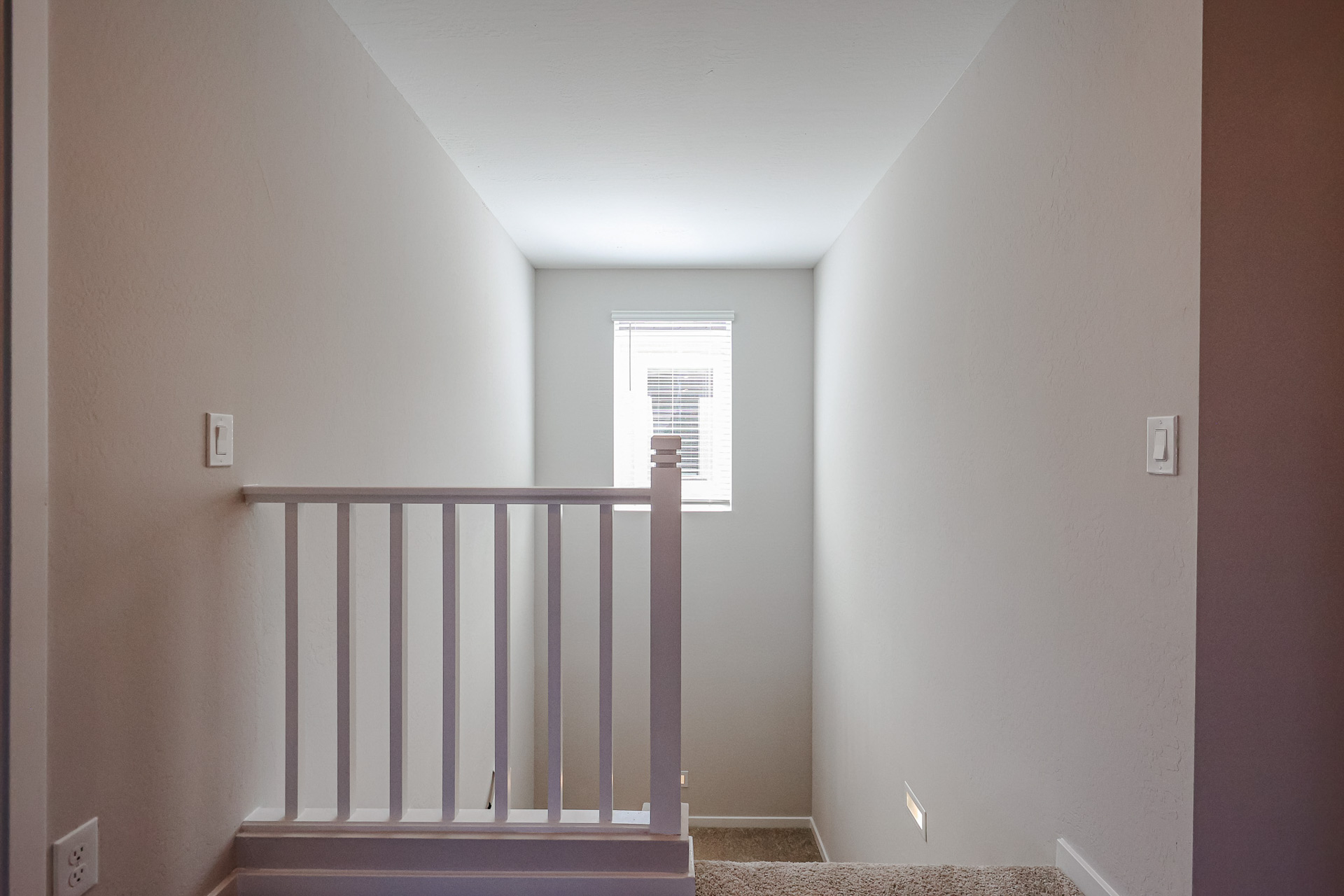 A white room with a black railing.