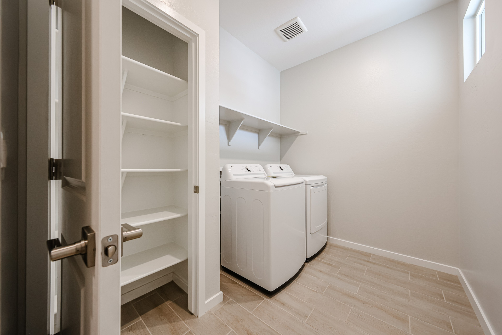 A white room with a white shelf and a white refrigerator.