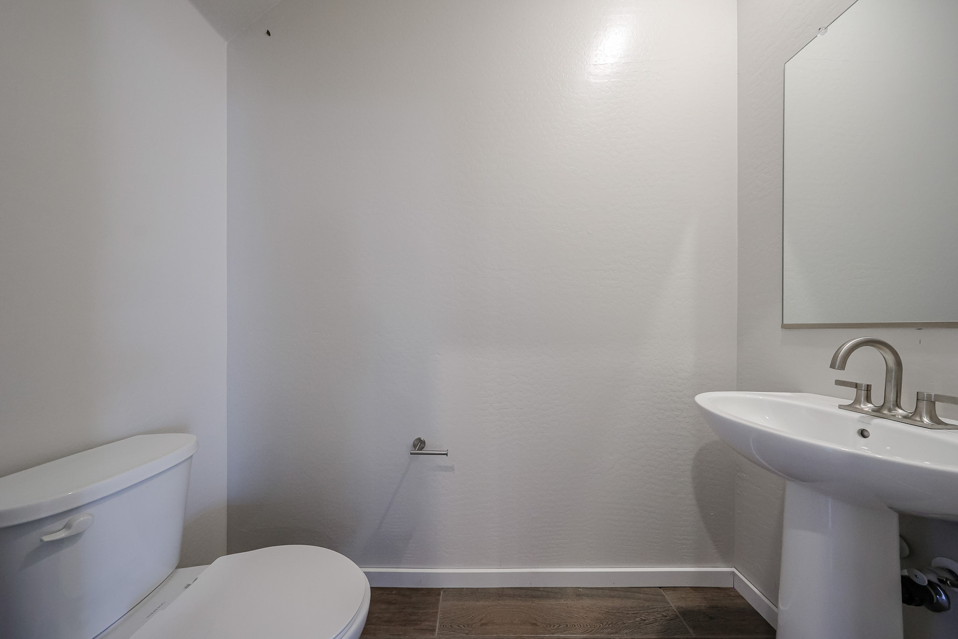 A bathroom with a toilet sink and a mirror.