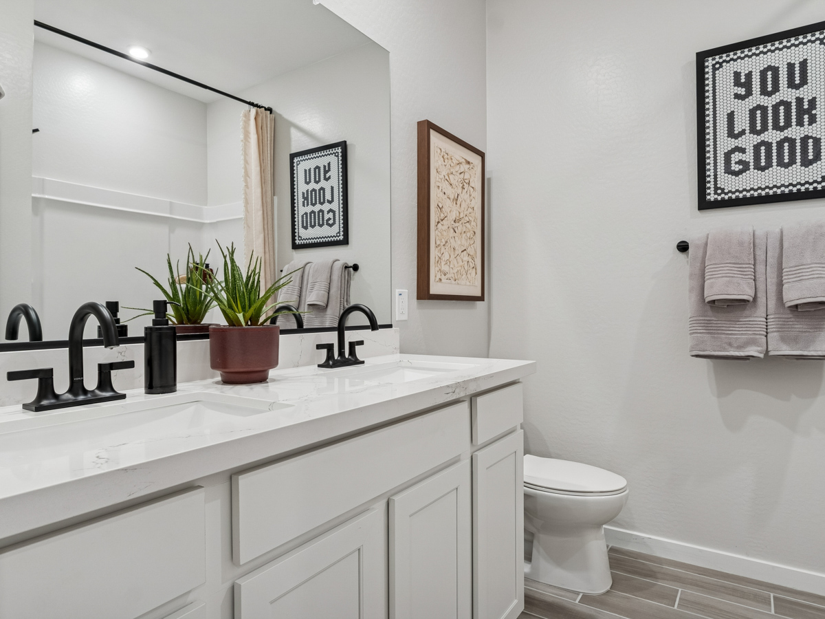A bathroom with a sink toilet and mirror.