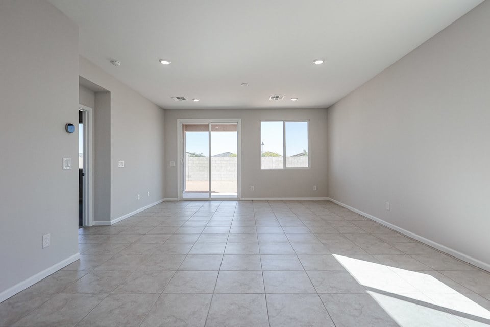 A large empty room with a tile floor and windows.