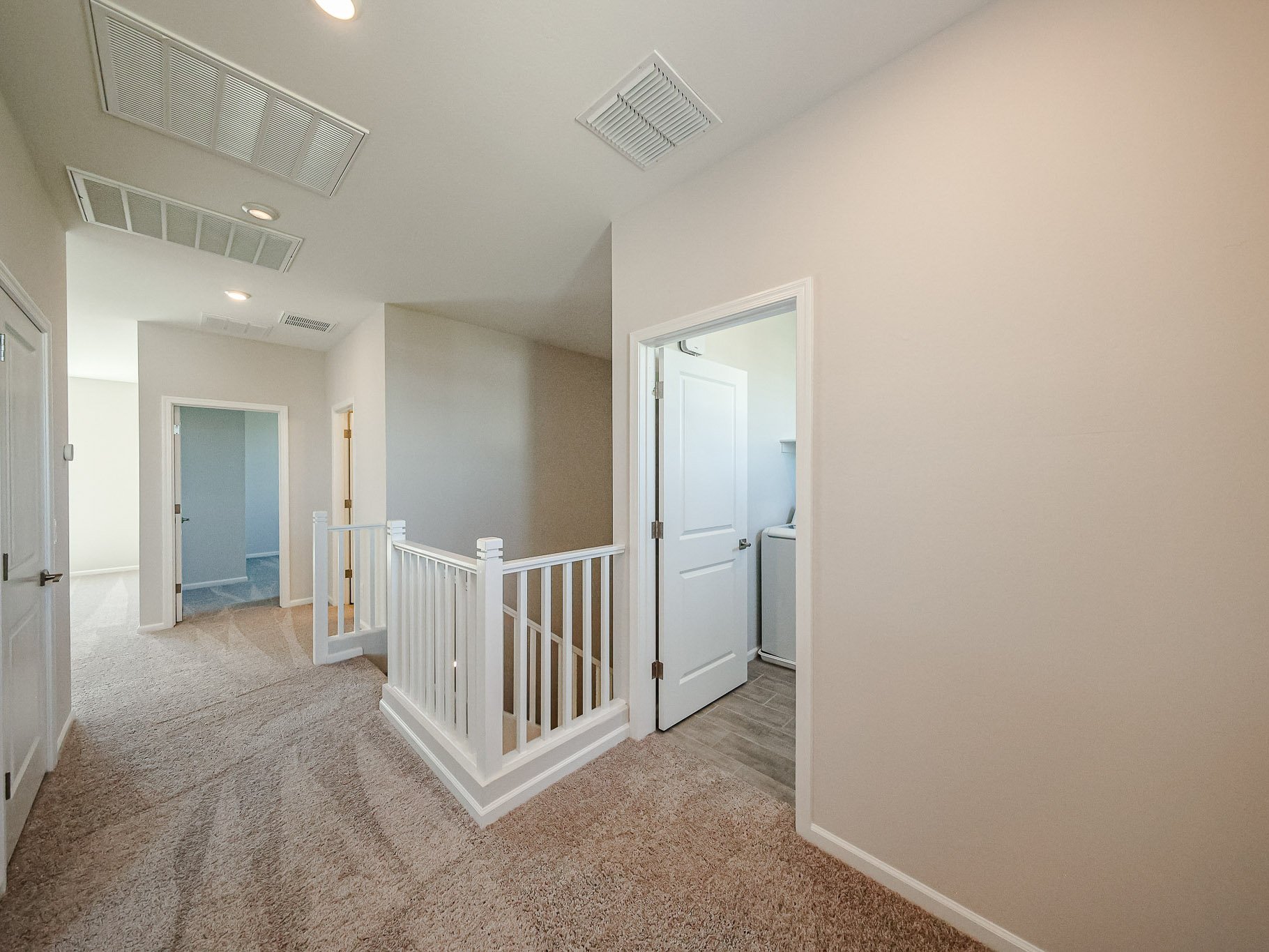 A room with a white railing and a white door.
