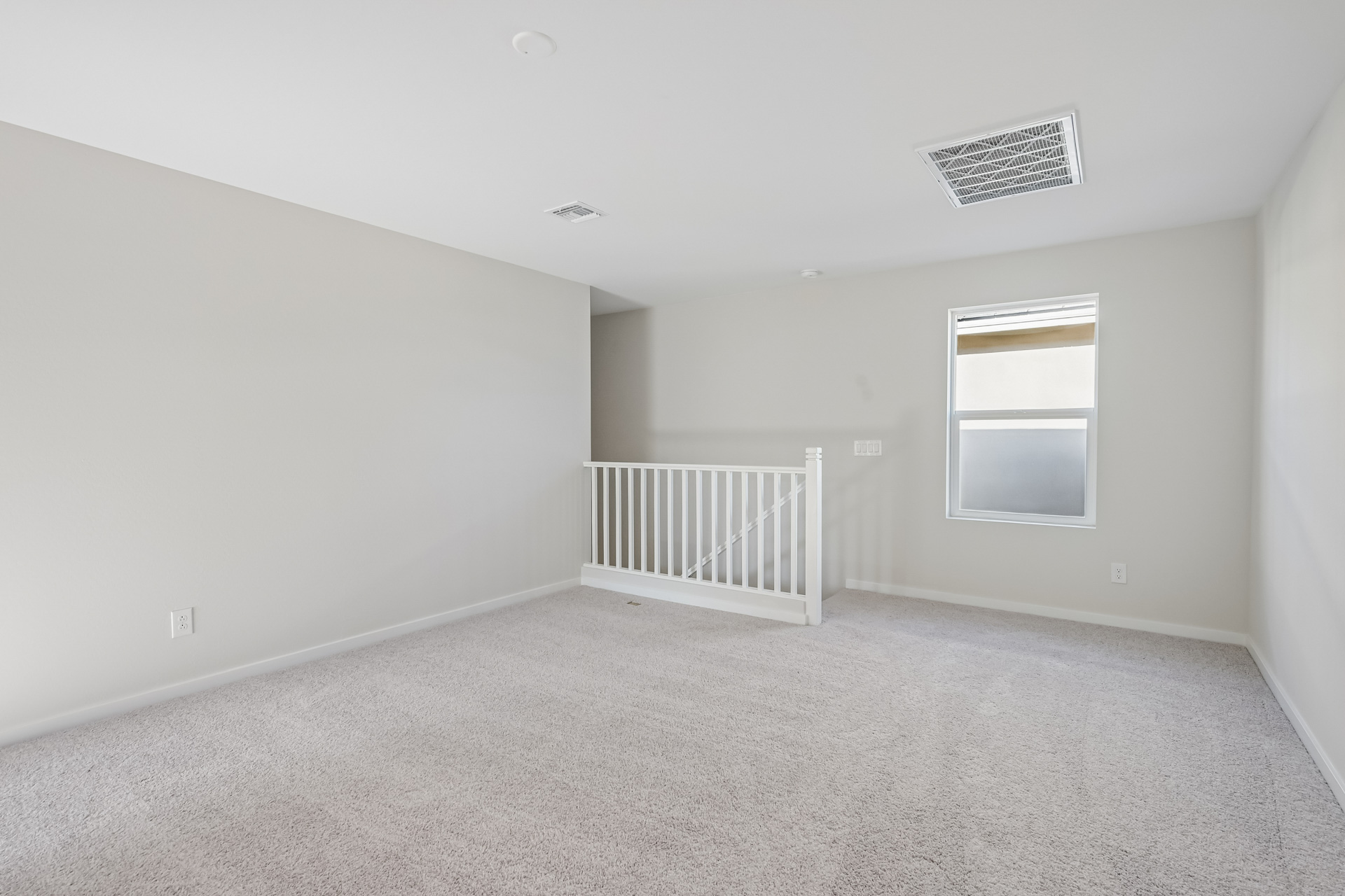A room with a white railing and a window.