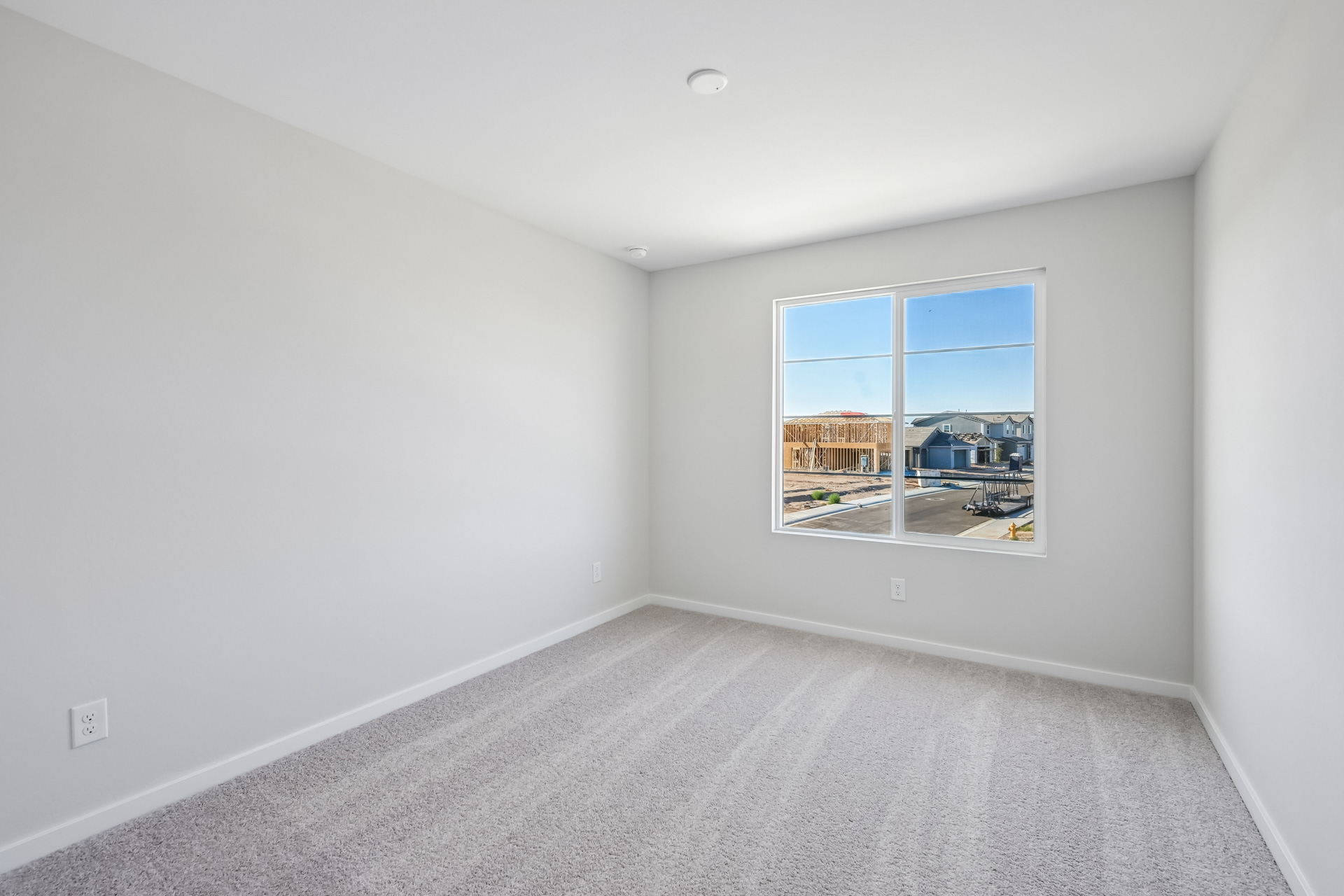 A room with a window and a white wall.