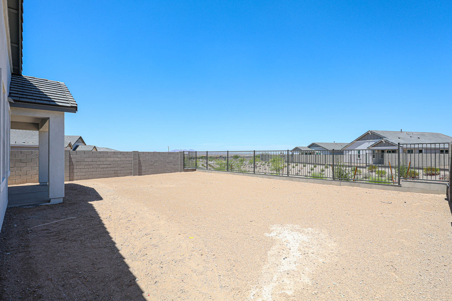 A sandy area with a fence and buildings in the background.