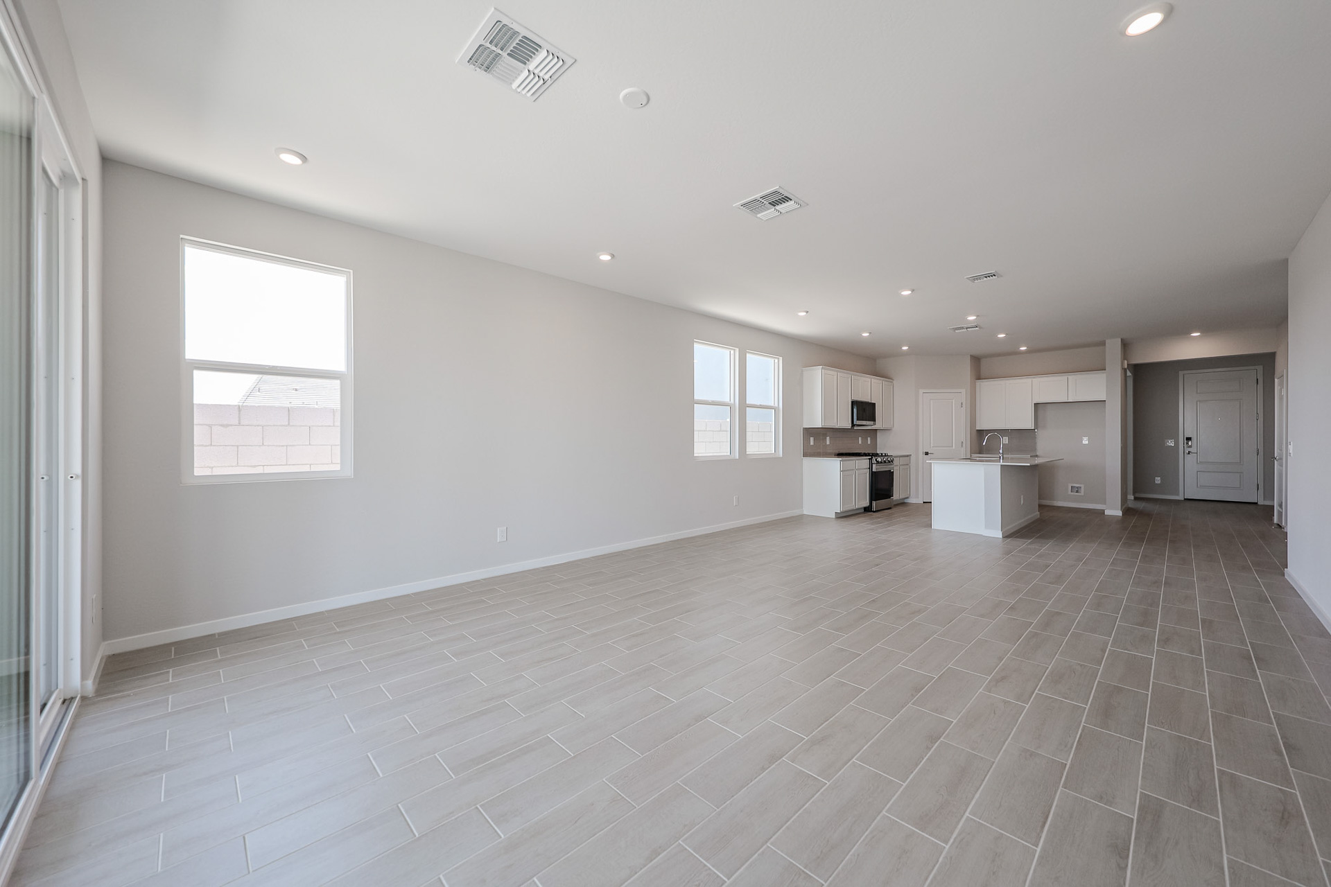 A large empty room with a tile floor and a wood floor.