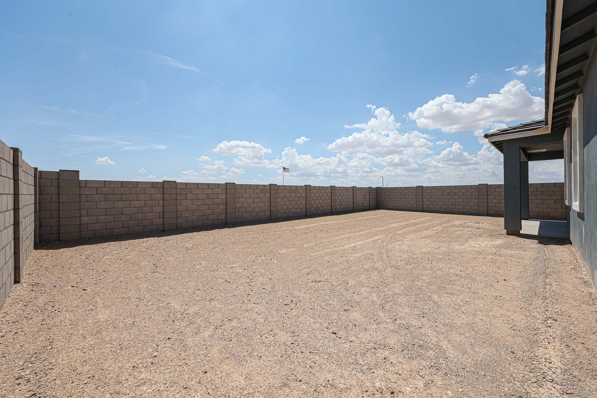 A dirt road with a fence and a building on the side.