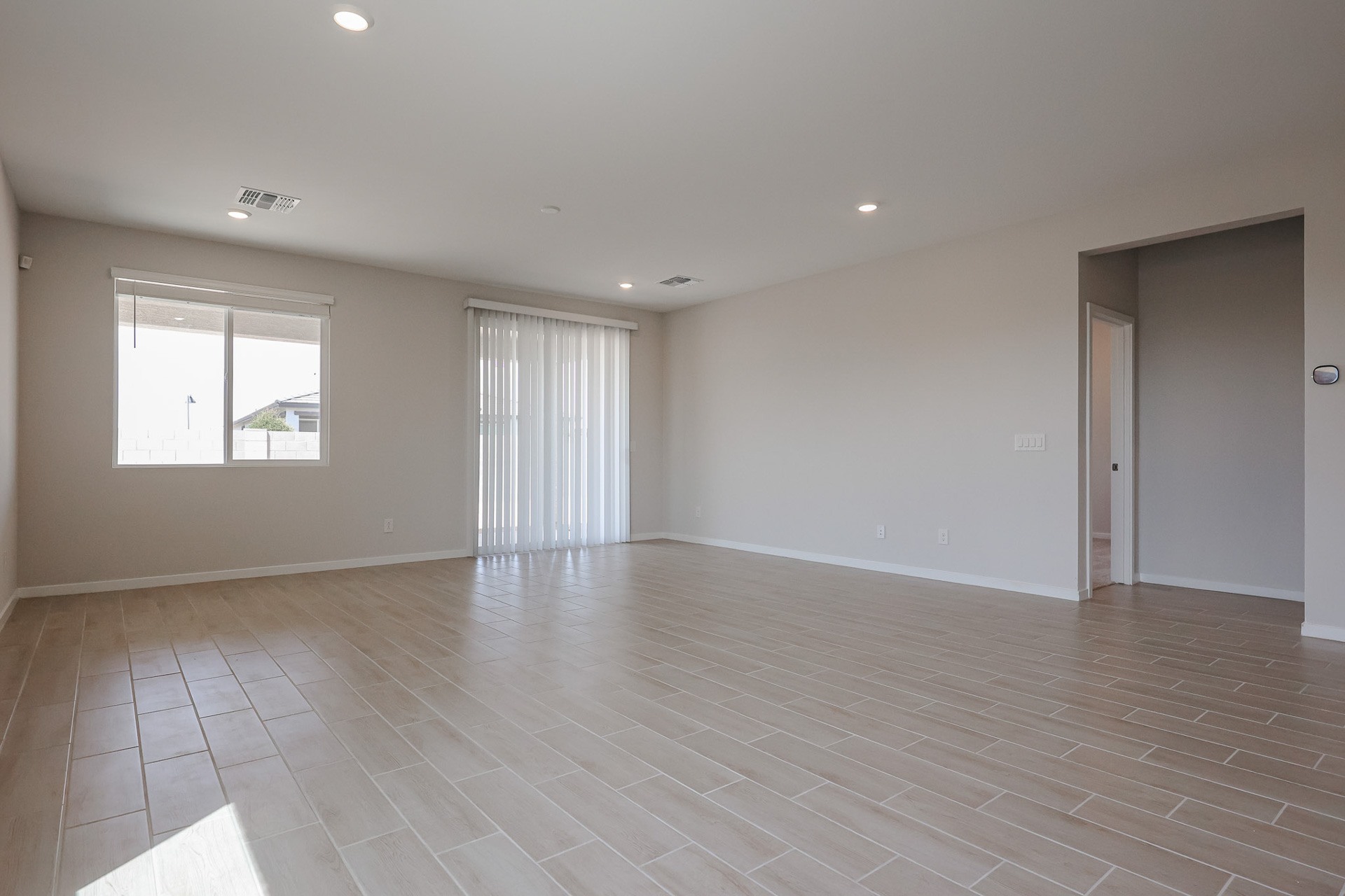 A room with a wood floor and white curtains.