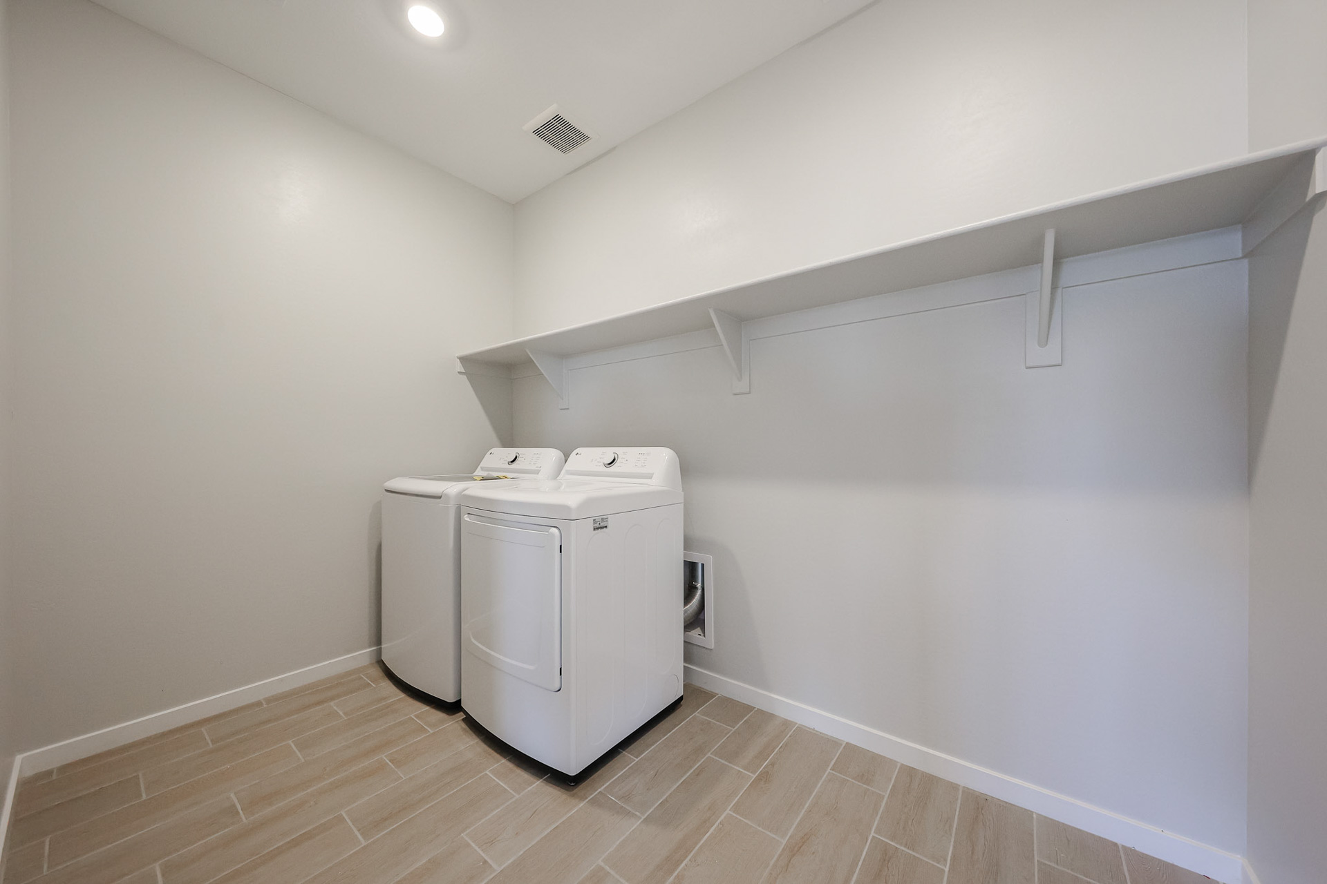 A white room with a white wall and a white refrigerator.