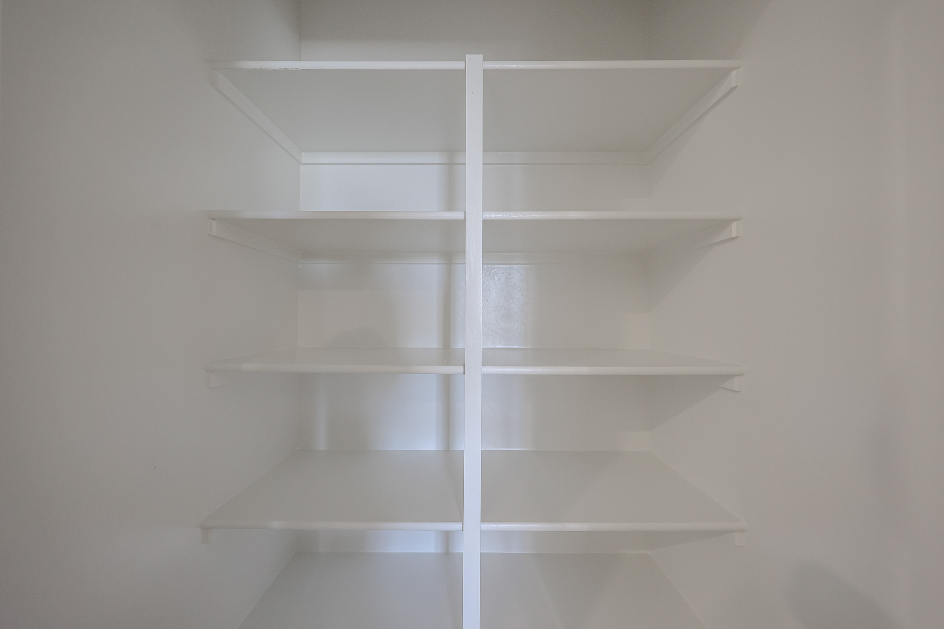 A white shelf with a white wall.