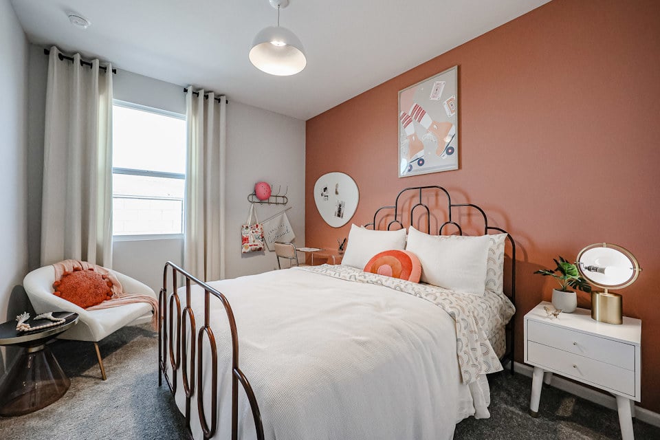 A bedroom with a bed and a chair.