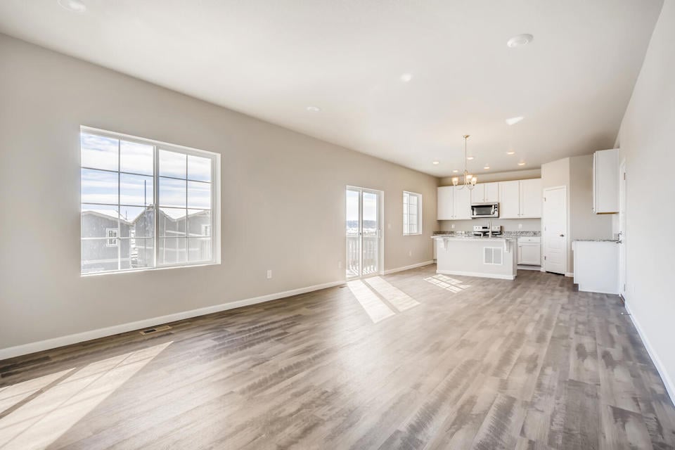 A large empty room with a wood floor and white cabinets.