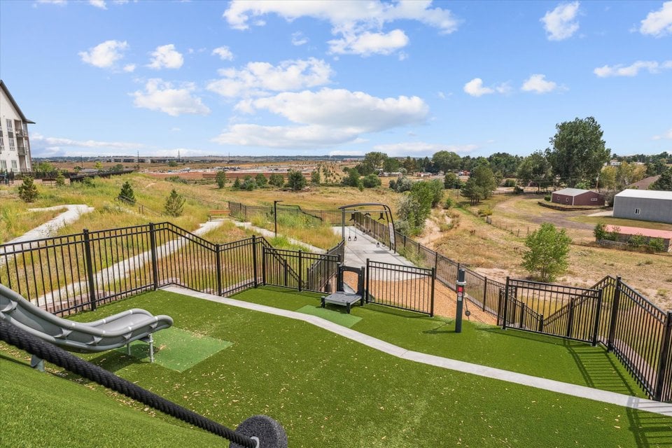 A fenced in yard with a small park and a small building.