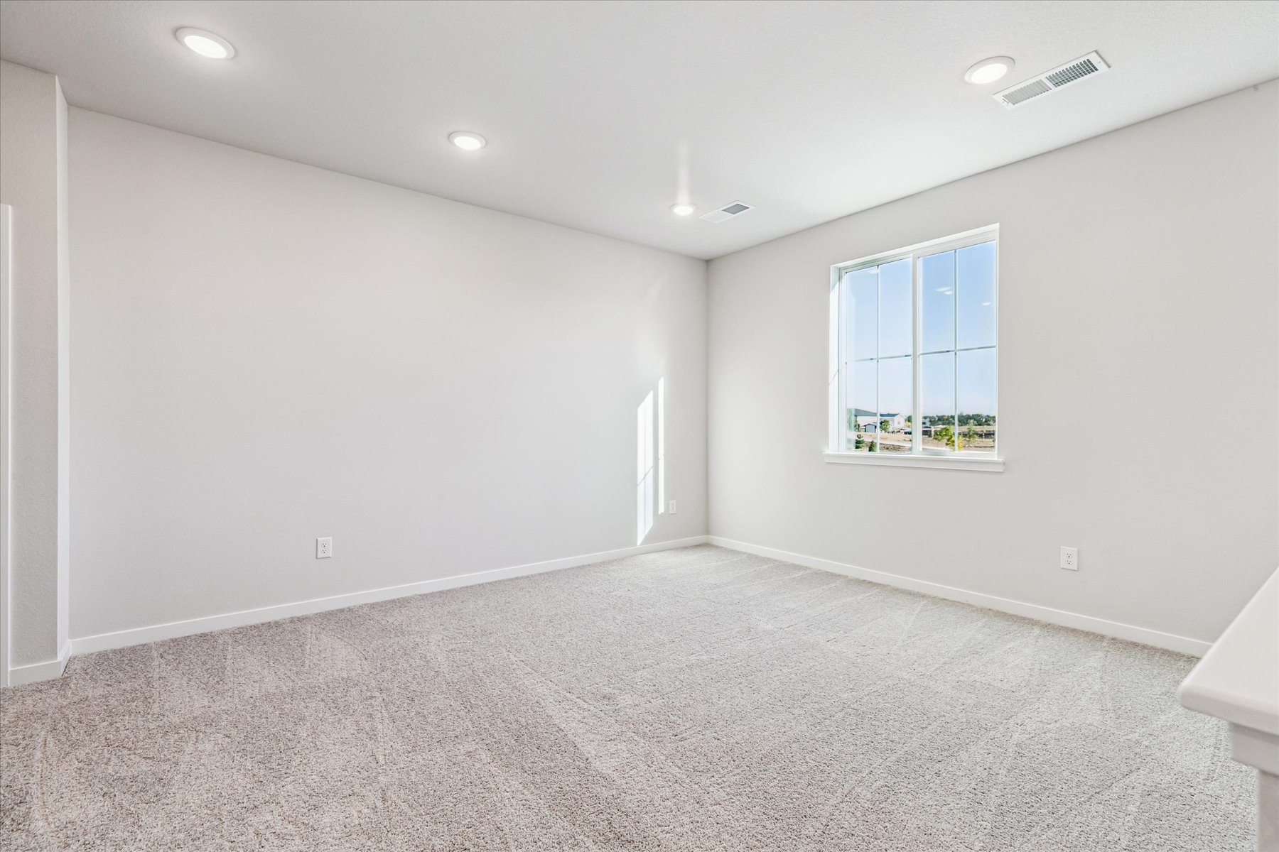 A room with a window and a white wall.