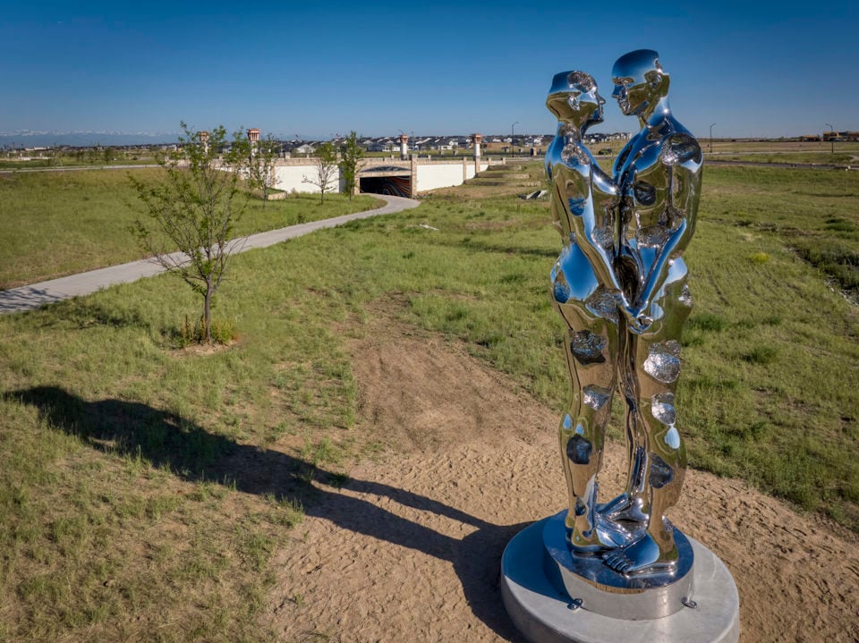 A couple of metal sculptures in a grassy field.