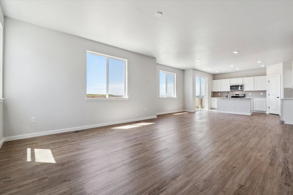 A large empty room with a wood floor and white cabinets.