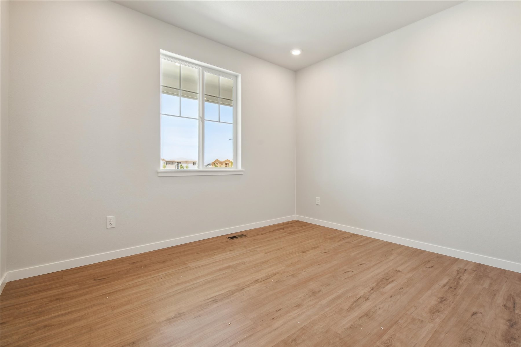 A room with a window and a wood floor.