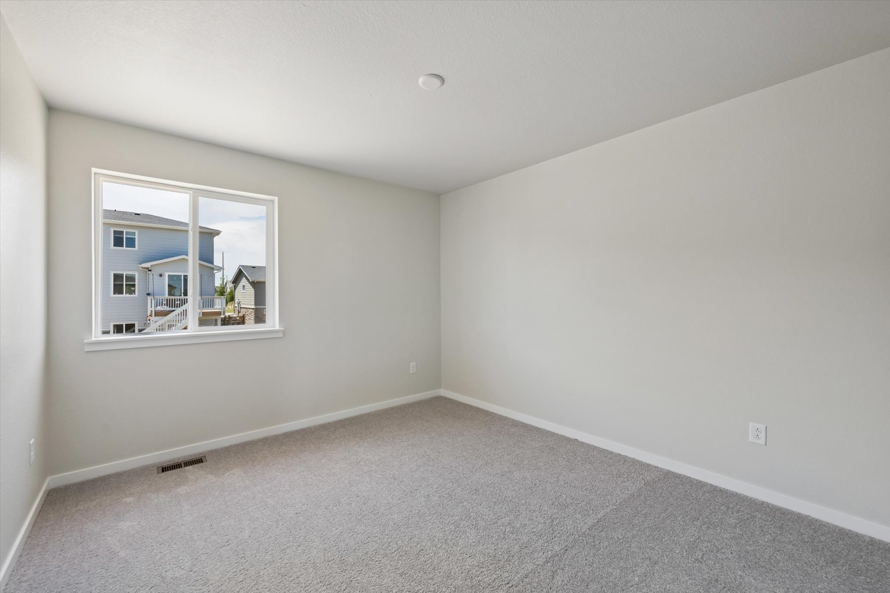 A room with a window and a white wall.