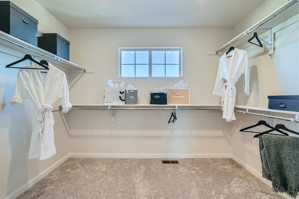 A room with white clothes on the wall and a window.