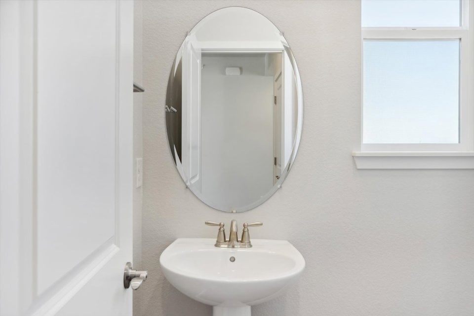 A bathroom with a round mirror.