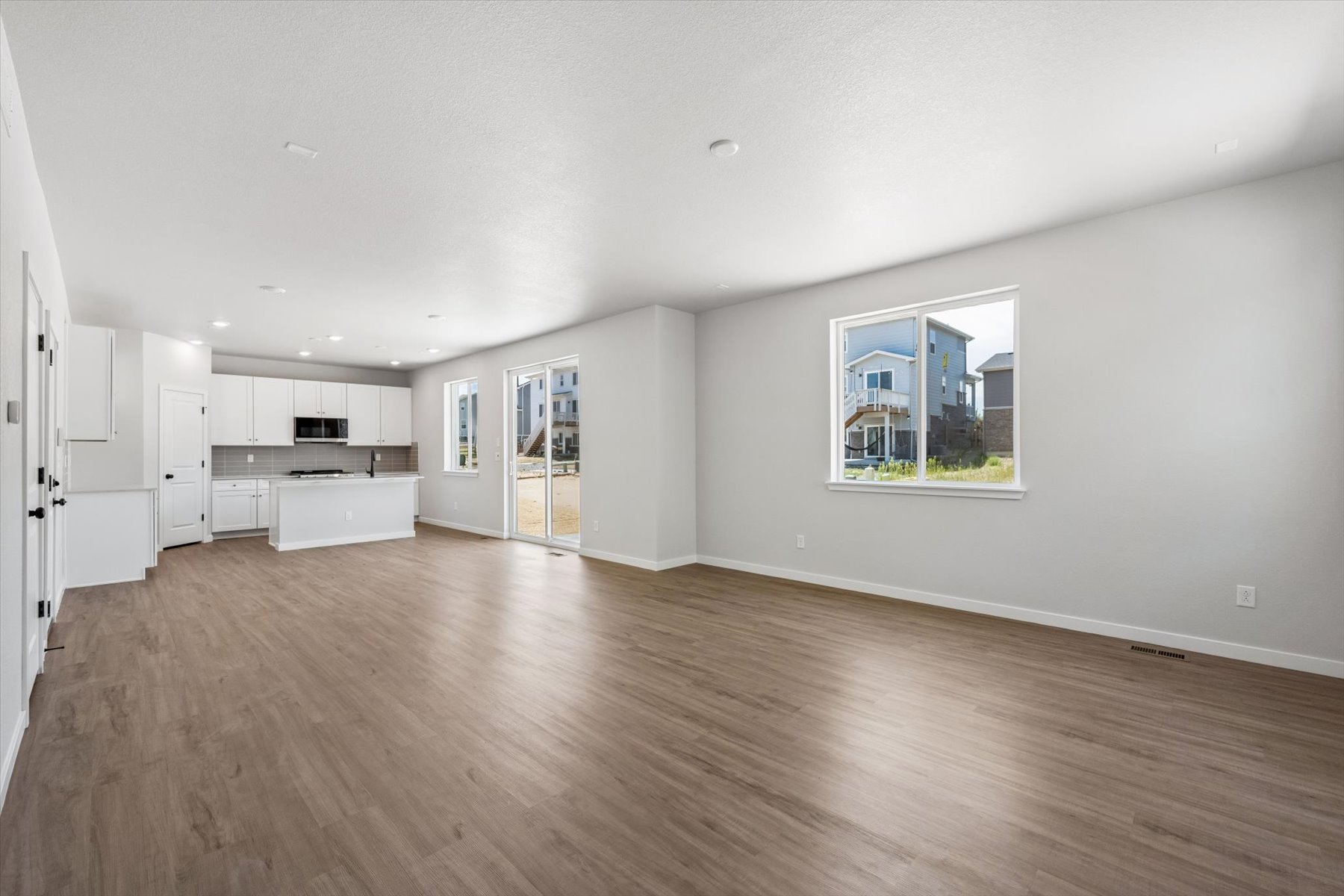 A large empty room with a wood floor and a window.