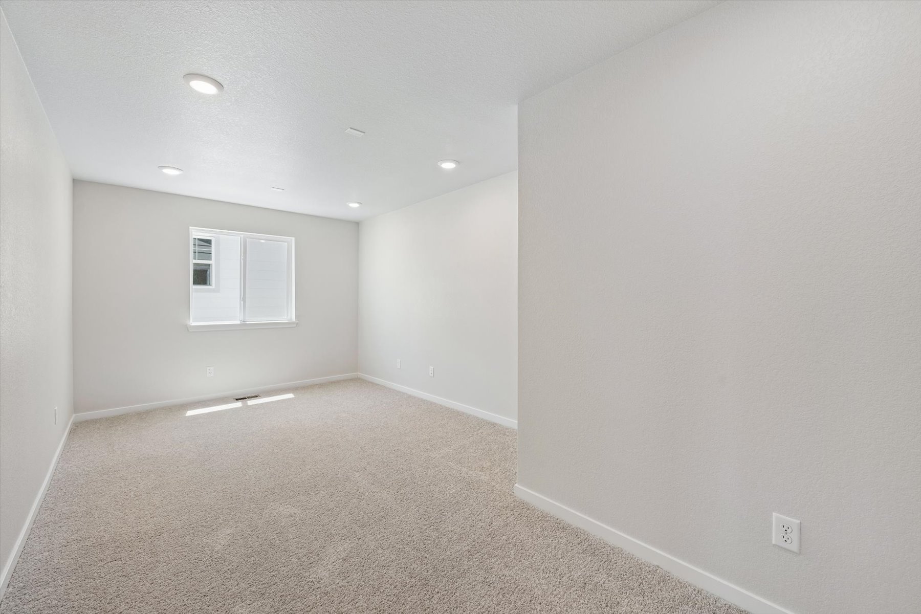 A room with a carpet and a white wall.