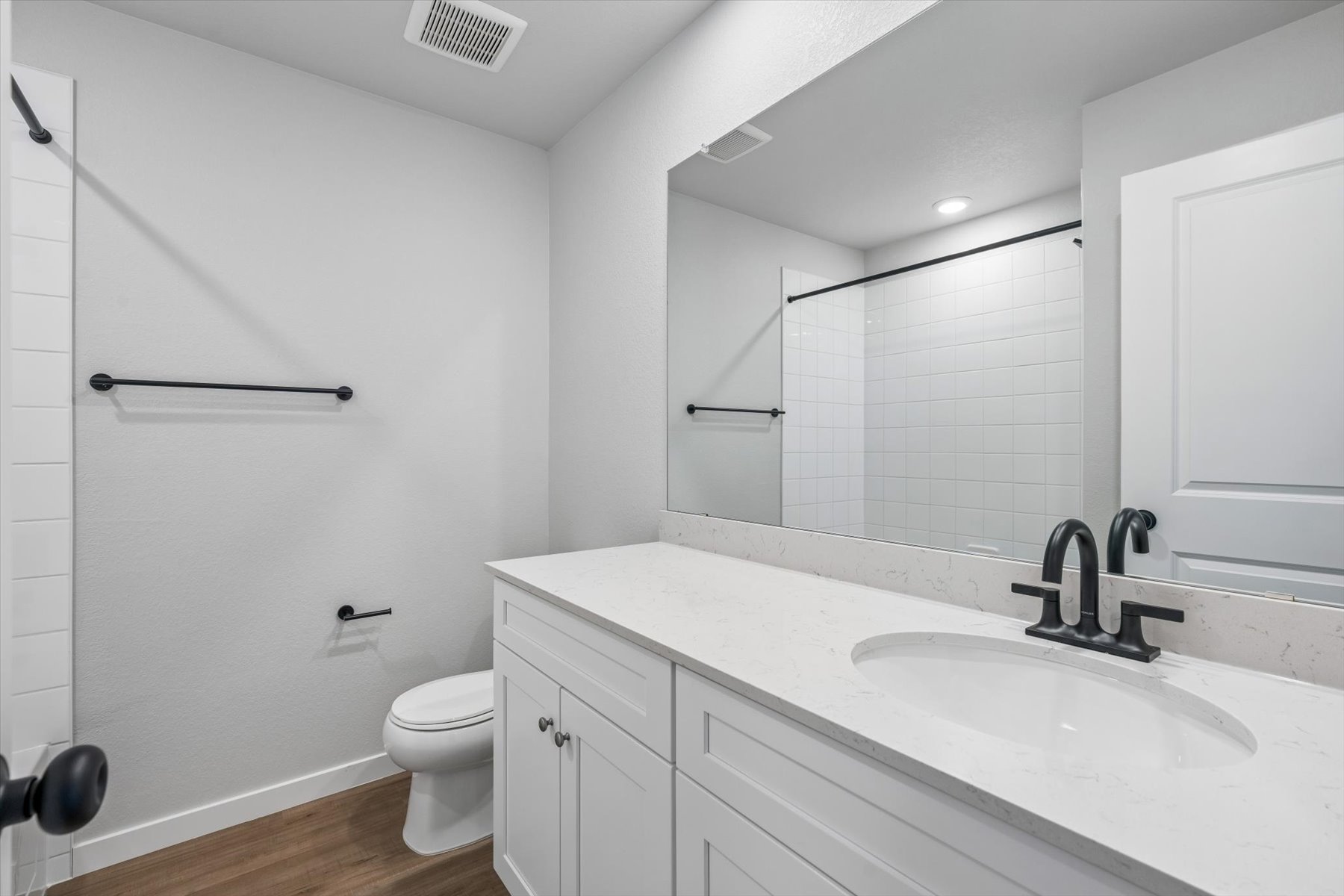 A bathroom with a sink toilet and mirror.