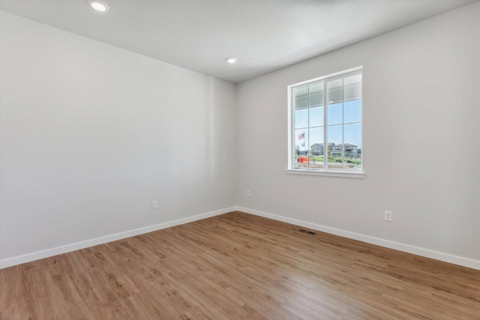 A room with a window and a wood floor.