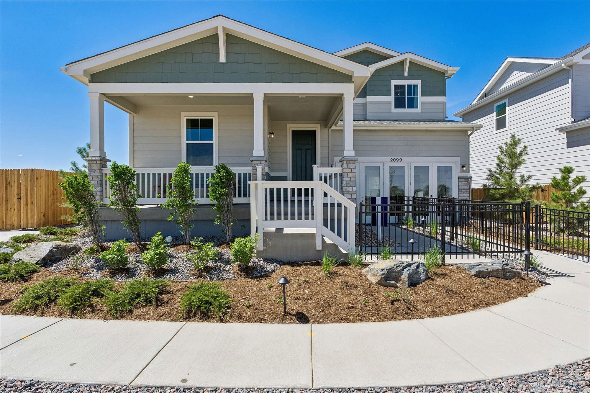 A house with a fence and bushes in front of it.